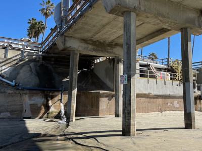 Water pours from pipe protruding from wall underneath Scripps Pier.